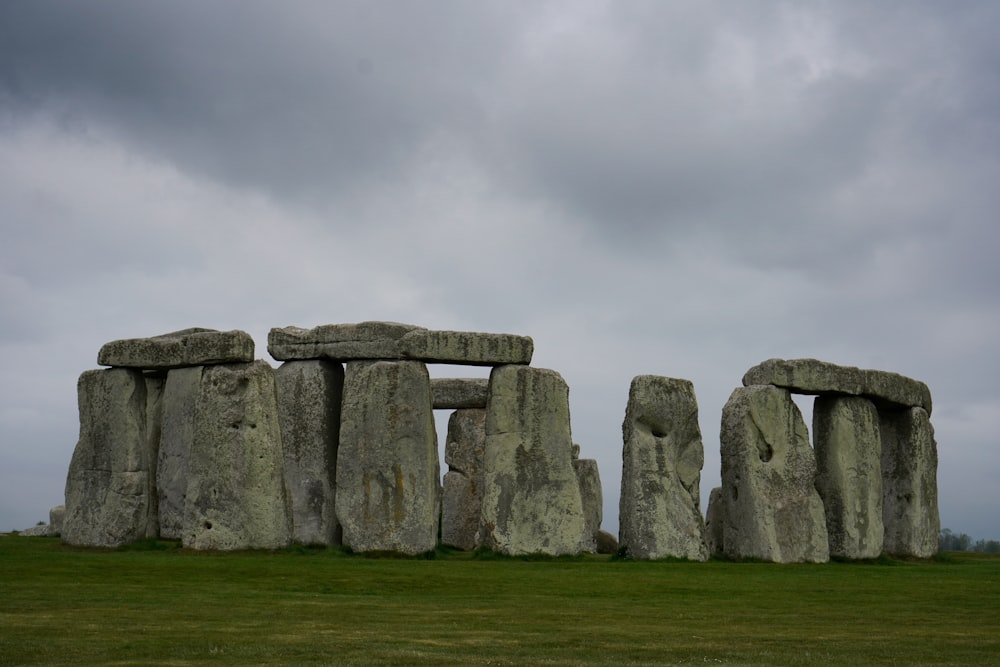 a stonehenge in a grassy field under a cloudy sky