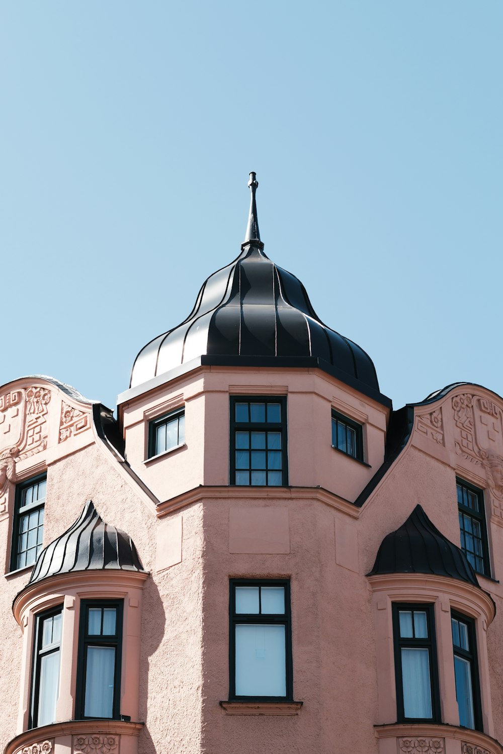 a large pink building with a black roof