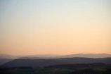 A serene landscape with gentle hills bathed in early morning light.