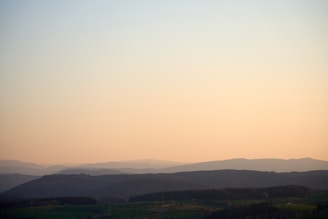 A serene landscape with rolling hills and a peaceful sunrise, symbolizing tranquility and reflection.