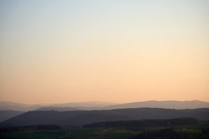 Soft earth tones of a peaceful landscape with rolling hills under a clear sky, evoking tranquility.