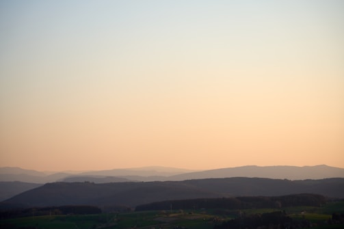 A serene earth-toned landscape with textured layers of hills and natural elements