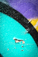 Close-up of a graffiti artist painting a wall with bright yellow and orange tones.