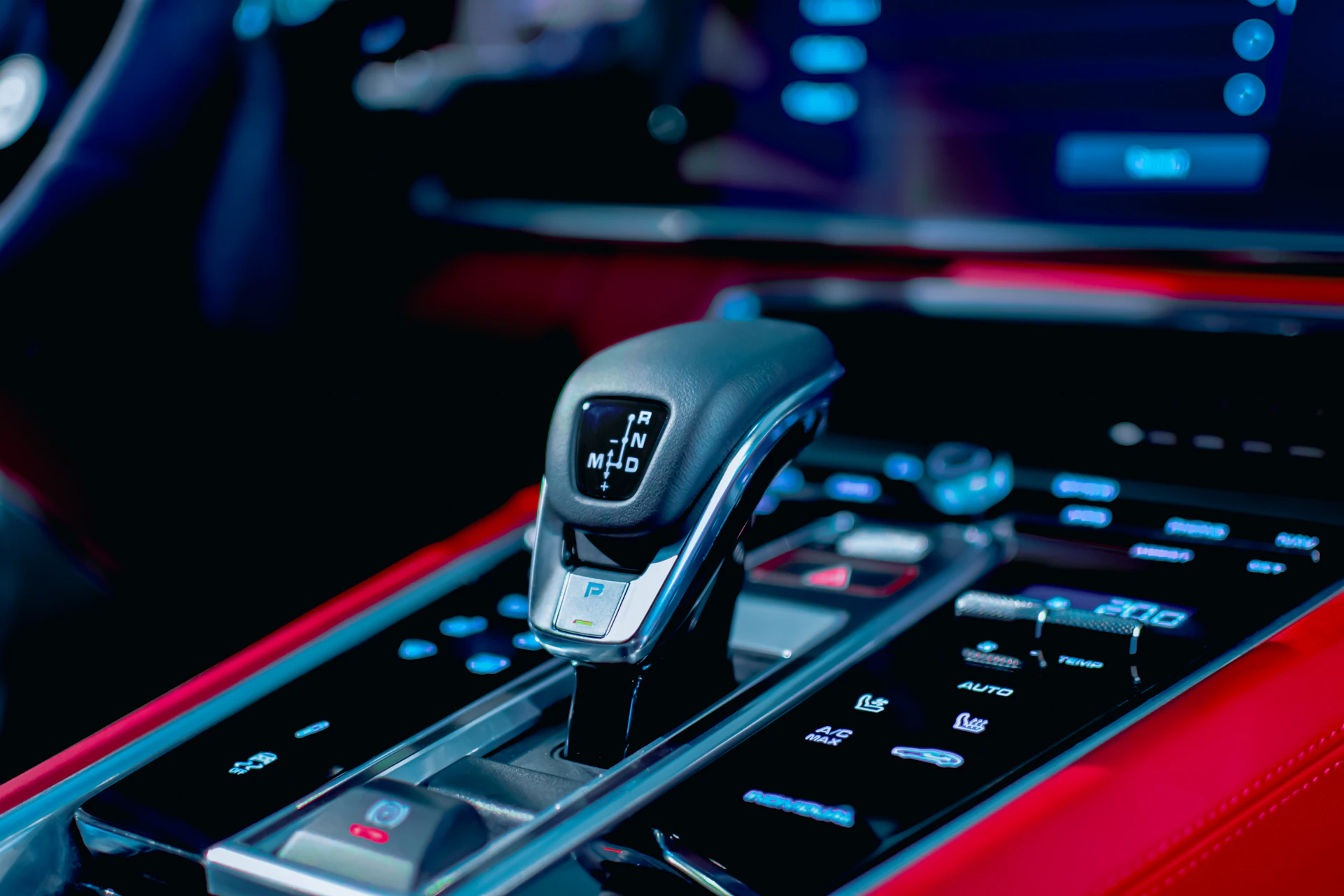 Close-up of a sleek car gear shift with a subtle red ambient light reflecting modern automotive design.