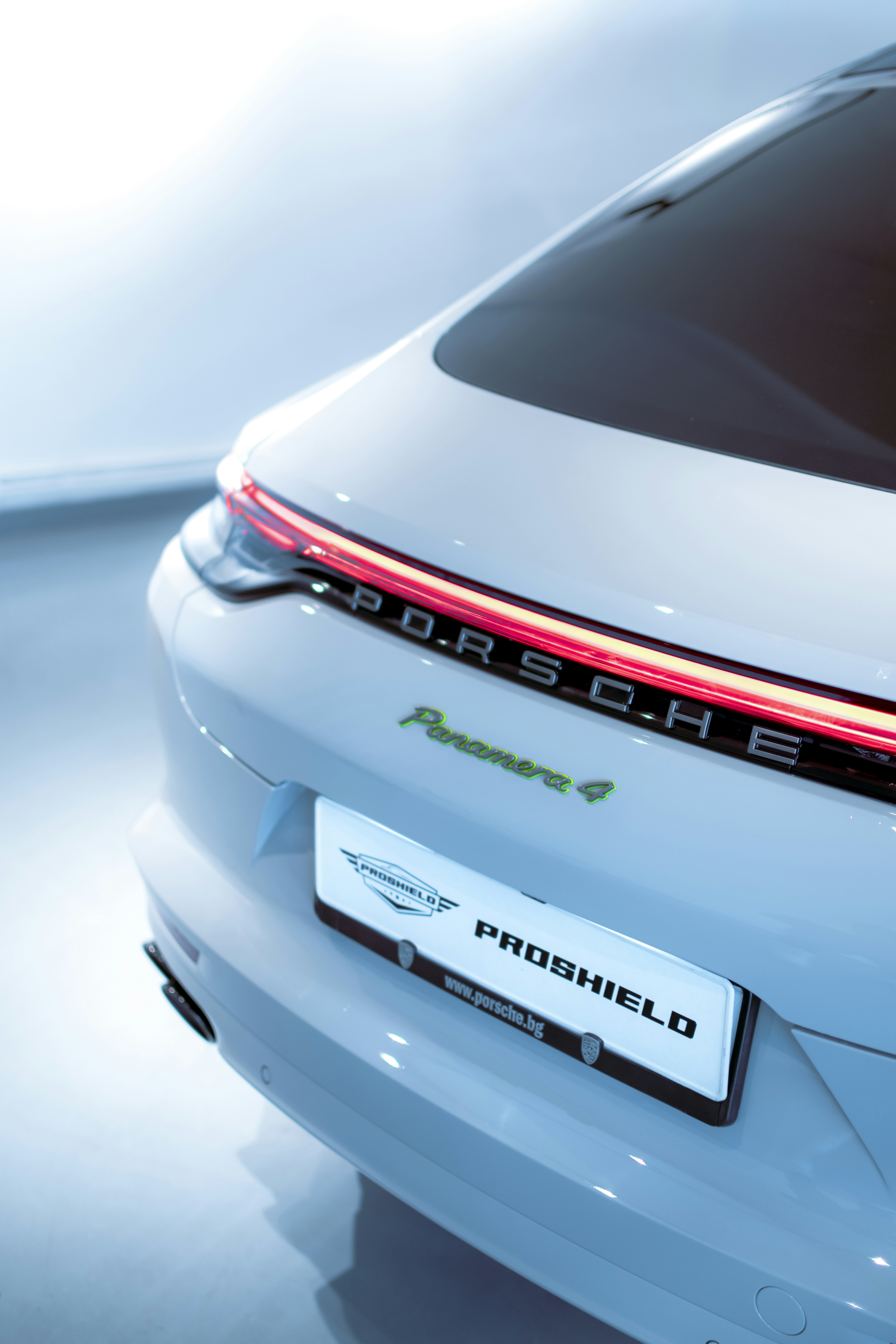 the back of a white porsche car with its lights on