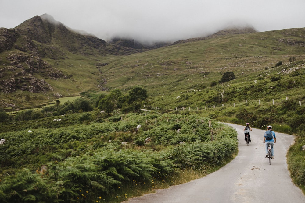 a couple of people riding bikes down a road