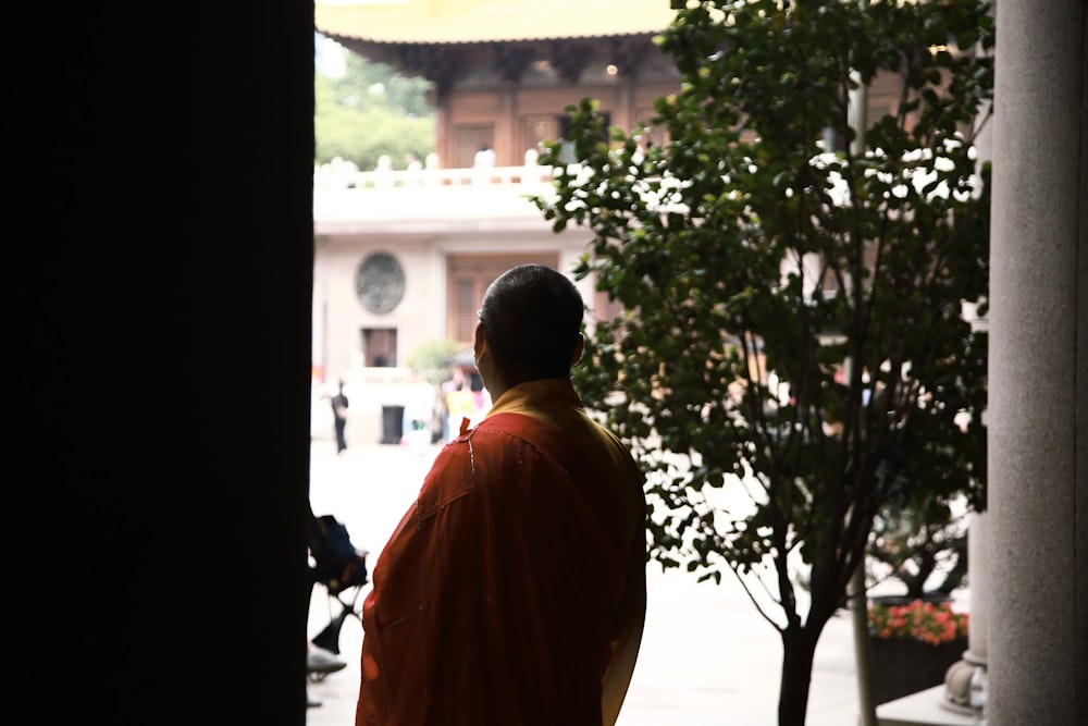 a man in an orange robe looking out of a doorway