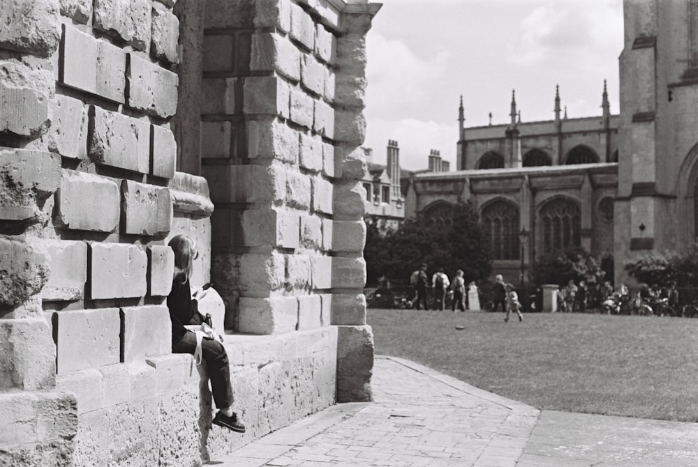 a young boy sitting on a stone wall in front of a building