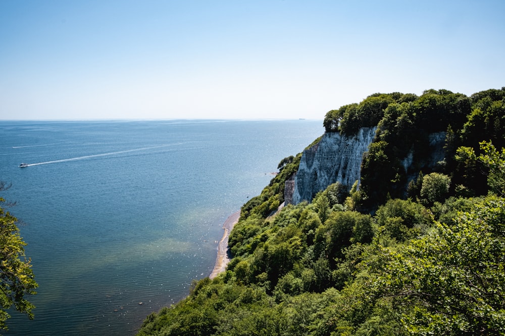 a boat is on the water near a cliff