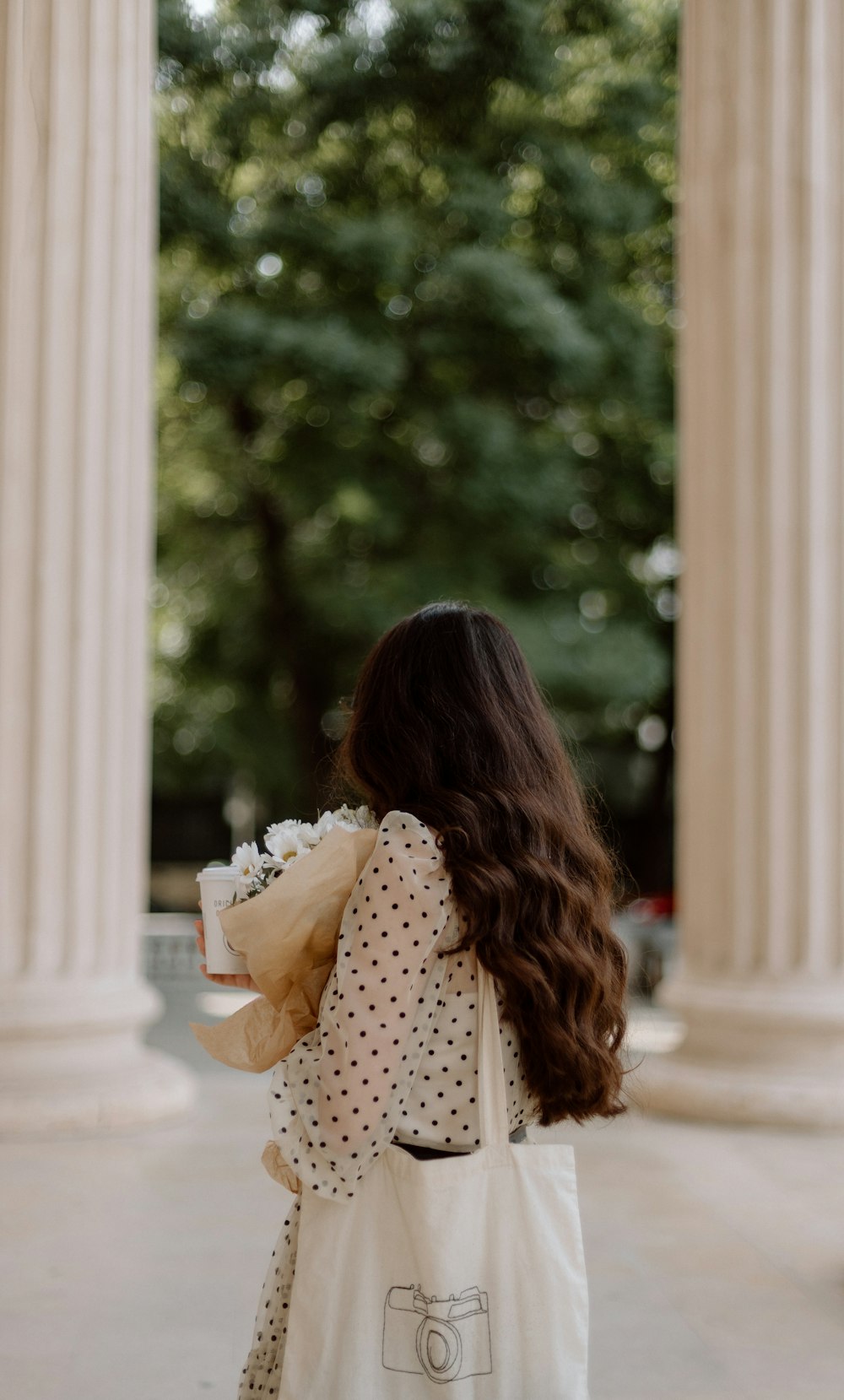 a woman carrying a white bag with a camera on it