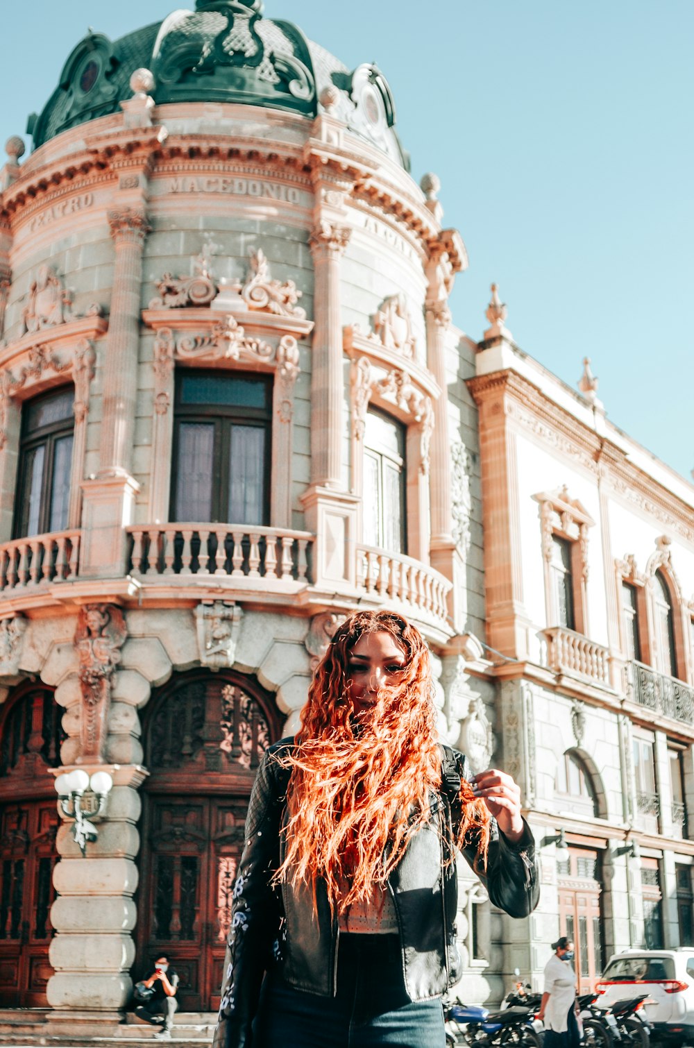 a woman with red hair standing in front of a building