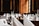 A luxurious dining setup featuring elegantly folded white napkins, sparkling glassware, and floral centerpieces arranged on round tables. The room is adorned with wooden paneling and framed portraits, creating an opulent and classic atmosphere.