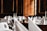 A luxurious dining setup featuring elegantly folded white napkins, sparkling glassware, and floral centerpieces arranged on round tables. The room is adorned with wooden paneling and framed portraits, creating an opulent and classic atmosphere.