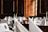 A luxurious dining setup featuring elegantly folded white napkins, sparkling glassware, and floral centerpieces arranged on round tables. The room is adorned with wooden paneling and framed portraits, creating an opulent and classic atmosphere.