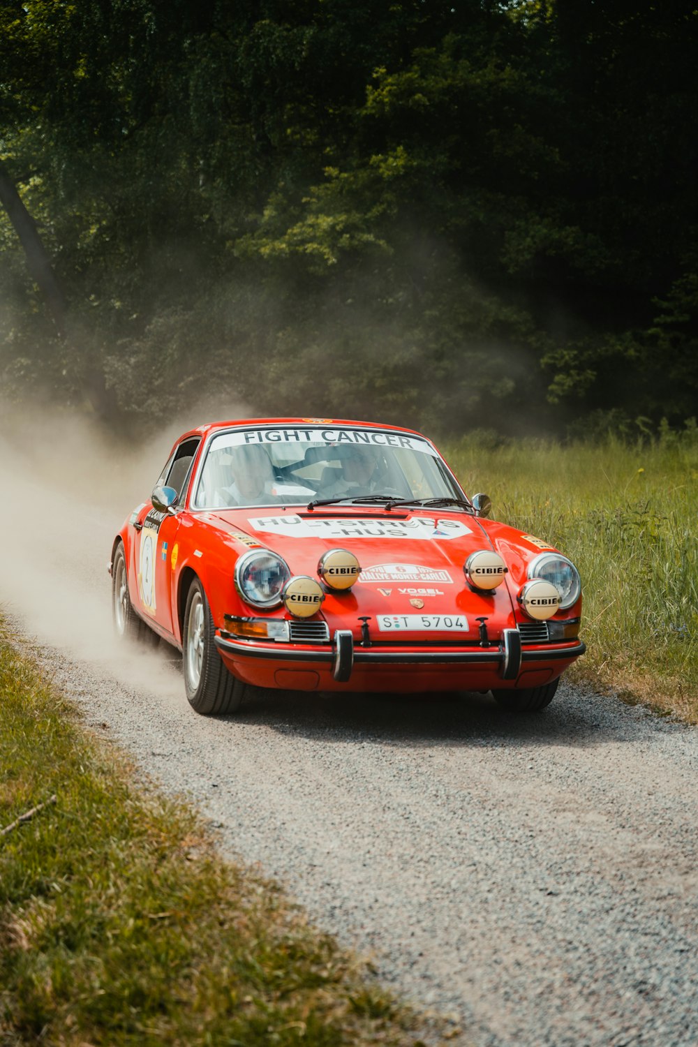 a red car driving down a dirt road