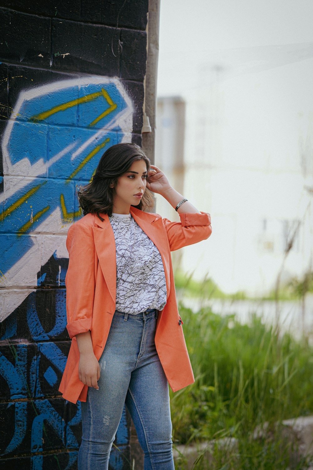 a woman standing next to a wall with graffiti on it