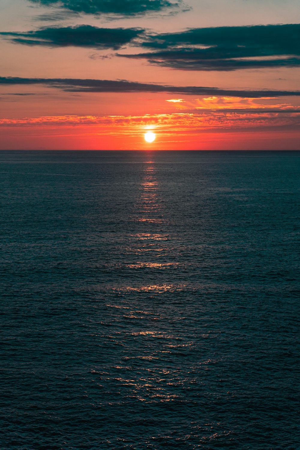 a large body of water with a sunset in the background