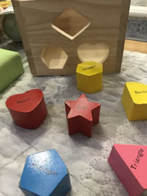 Close-up of hands assembling a colorful wooden shape sorter.