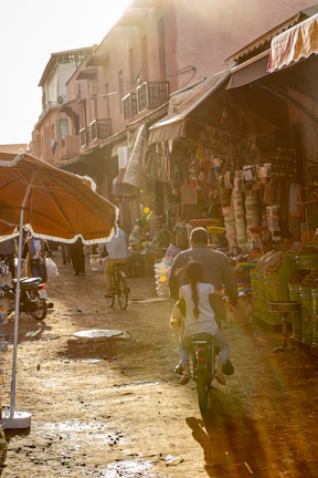 A sunlit street corner in a bustling foreign city, with colorful market stalls and locals going about their day.