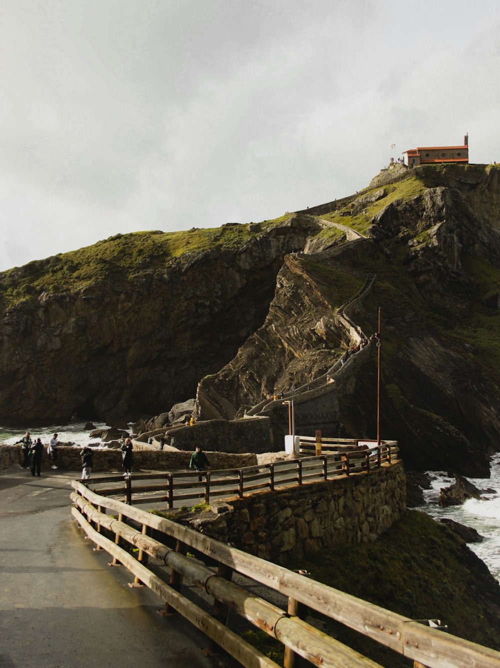 a wooden fence on the side of a road next to the ocean