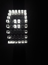 A geometric arrangement of multiple small, rectangular light cubes emitting a bright, white light against a dark background. The cubes are organized in a grid-like, three-dimensional structure, creating a striking visual effect.