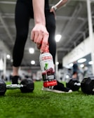 Strongbuild 100ml liquid chalk bottle resting on a gym bench next to weights.