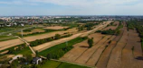 A panoramic view of lush green agricultural land with a city skyline in the distance.