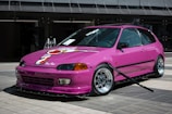 a pink car parked in front of a building