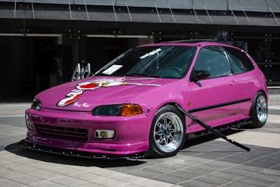 a pink car parked in front of a building