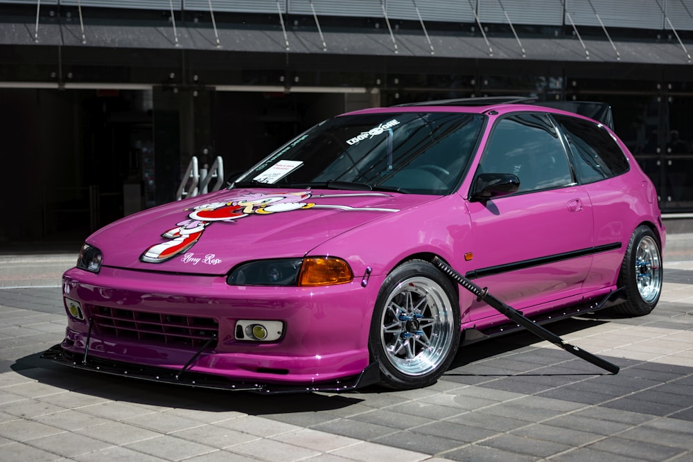 a pink car parked in front of a building