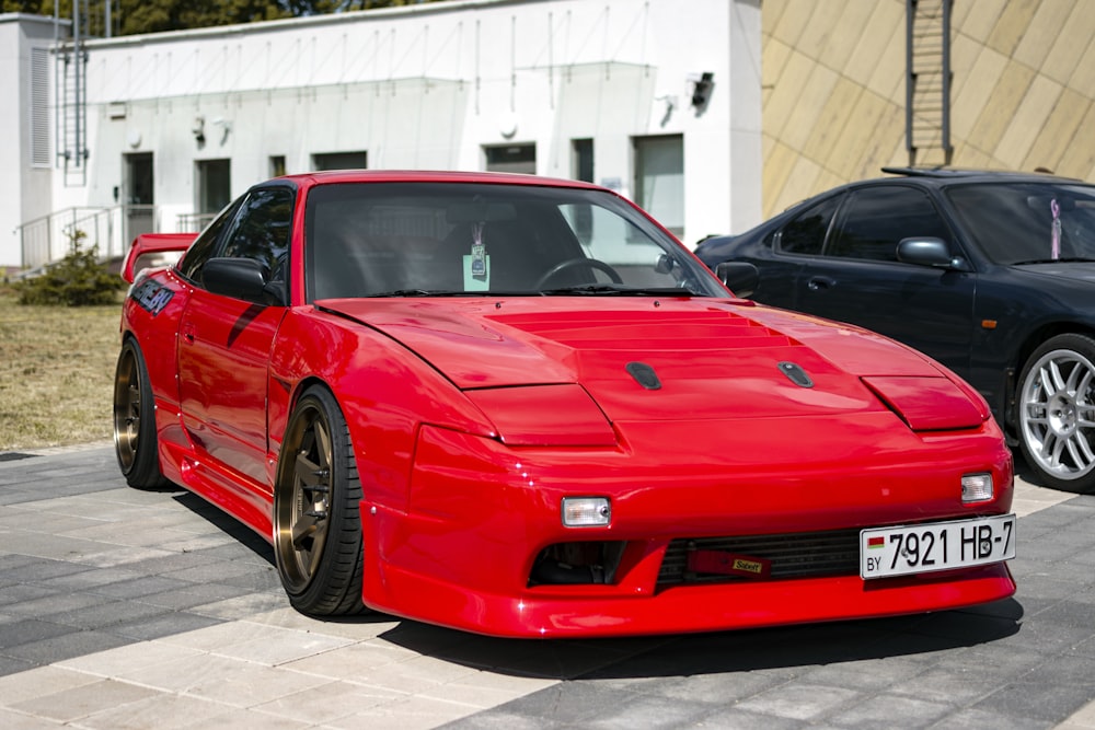 a red sports car parked next to a black car