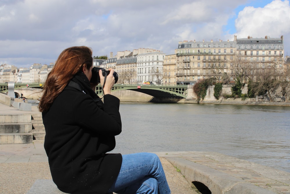 a woman taking a picture of a river with a camera