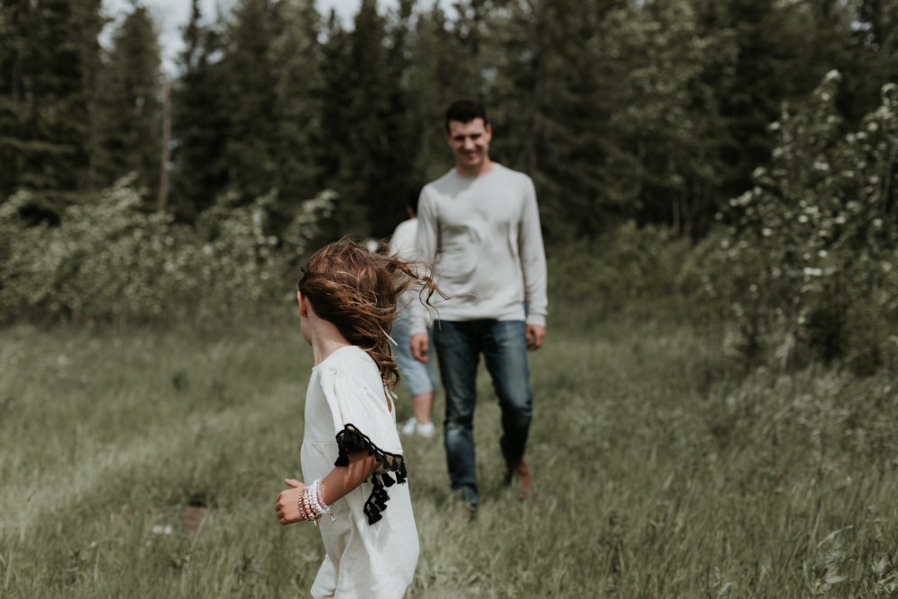 a man and a little girl walking through a field