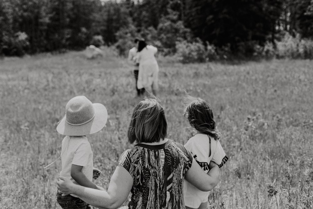 a black and white photo of a family walking through a field