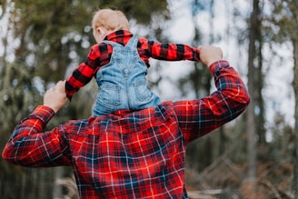 a man holding a child in his arms in the woods