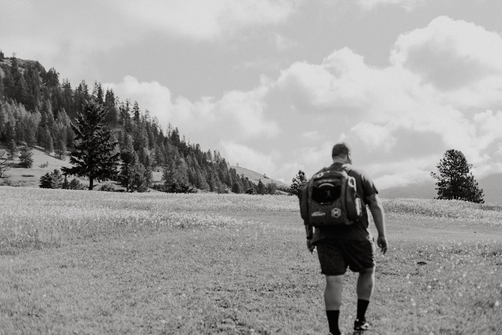 a man with a backpack walking through a field