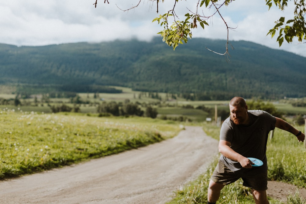 a man holding a frisbee on a dirt road