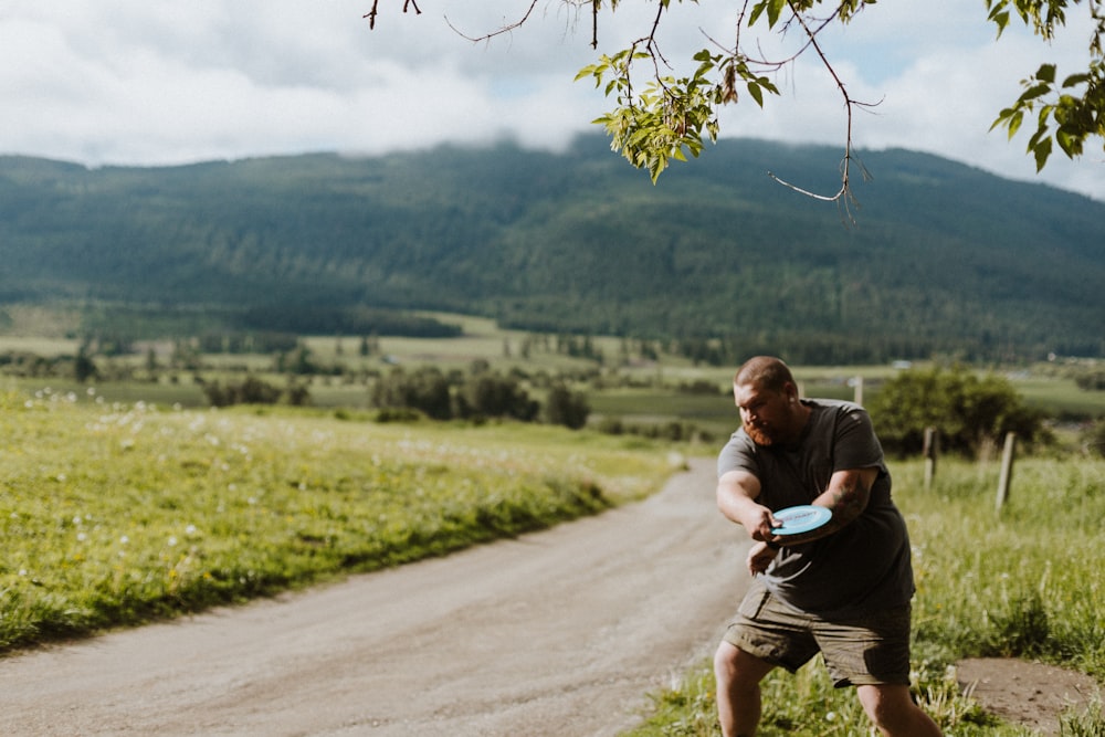 a man throwing a frisbee on a dirt road