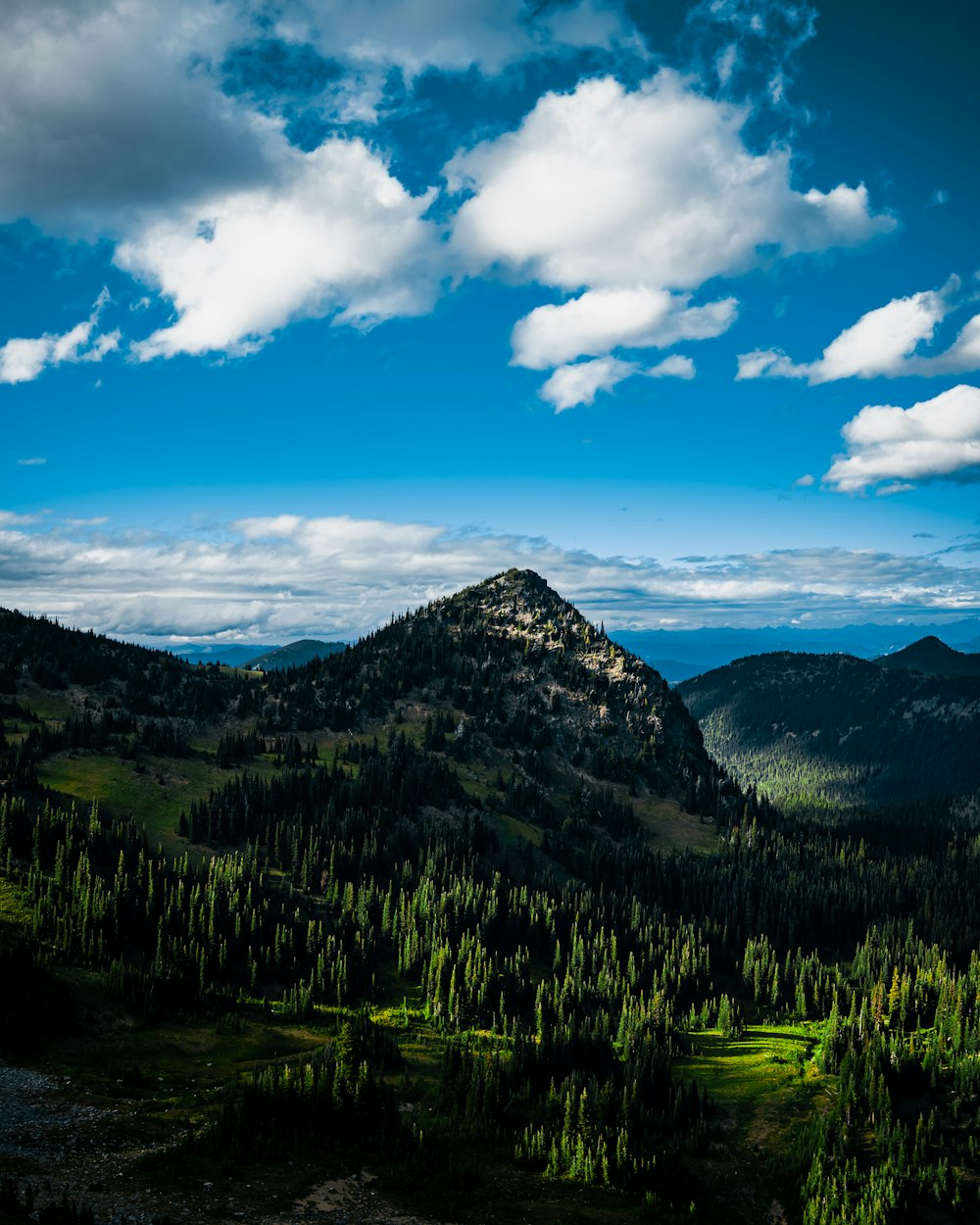 a view of a mountain with trees and clouds in the sky