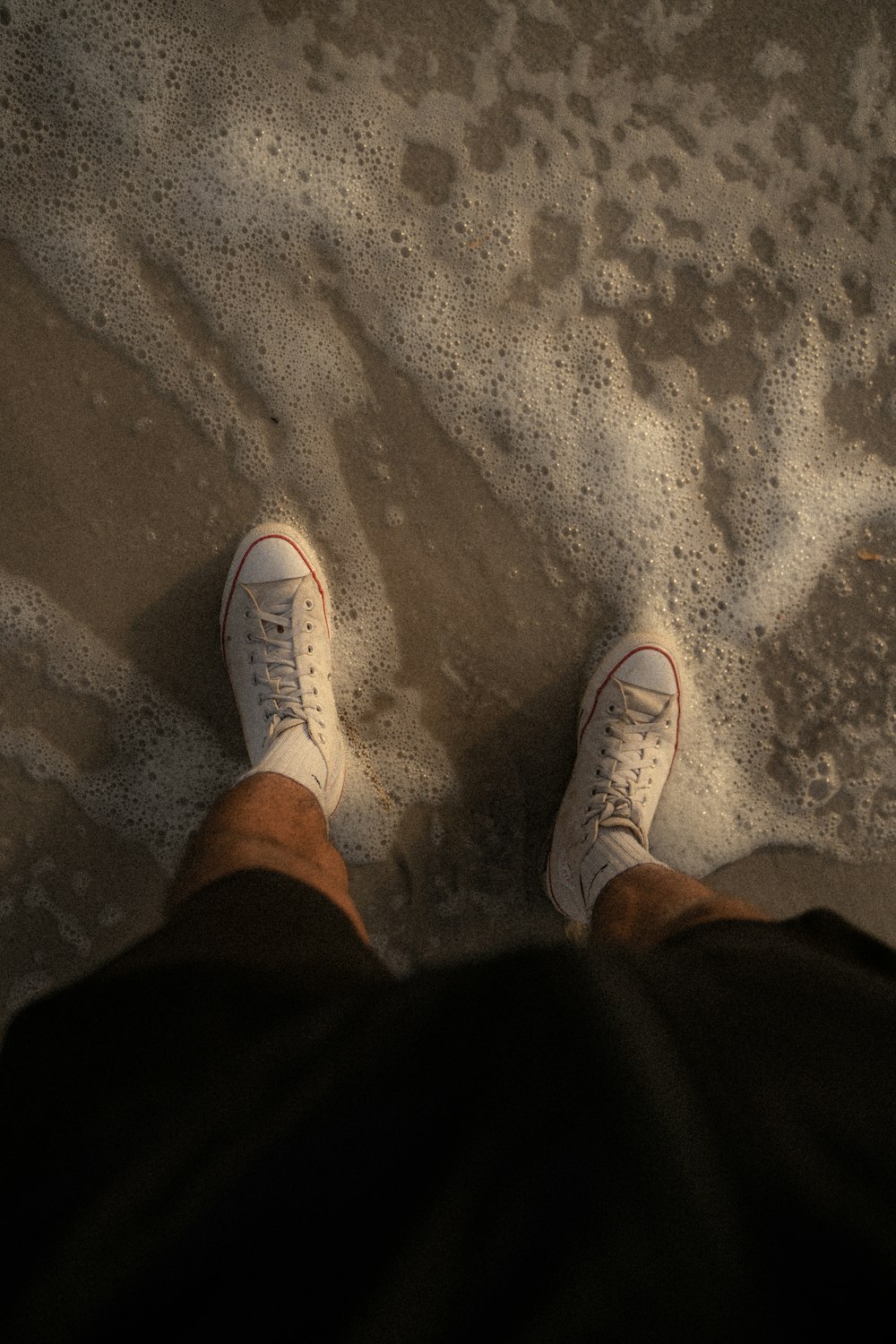 a person standing on a beach with their feet in the sand