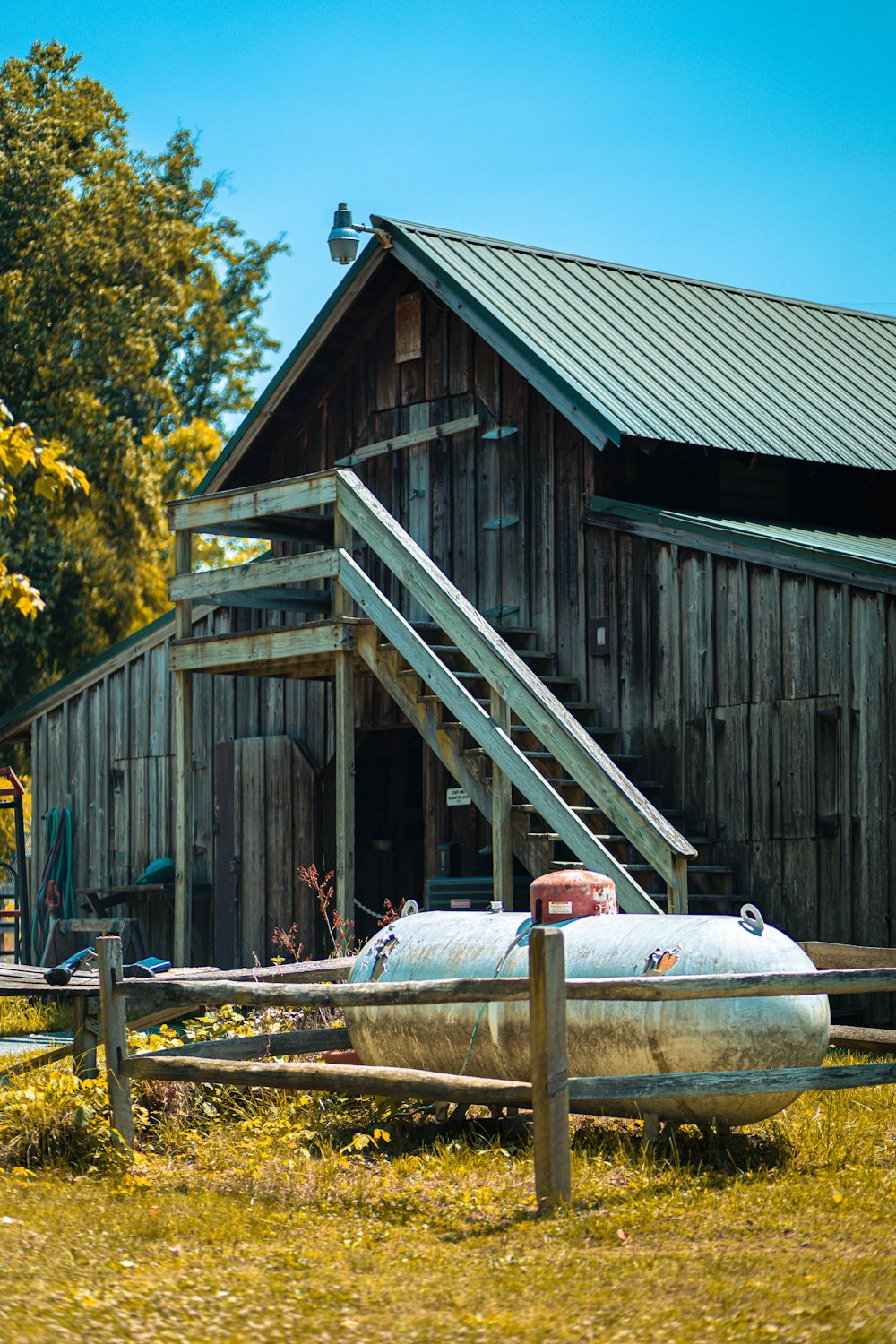 a wooden barn with a water tank in front of it