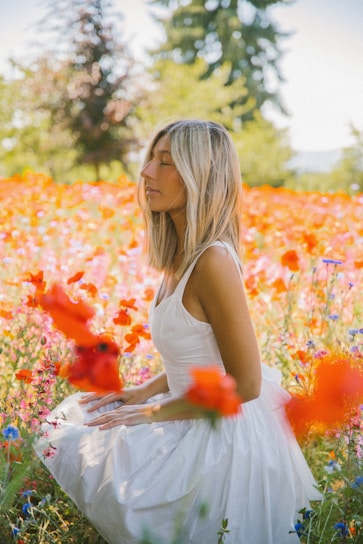 A vibrant outdoor scene with a young woman wearing a colorful, flowy dress surrounded by blooming wildflowers.