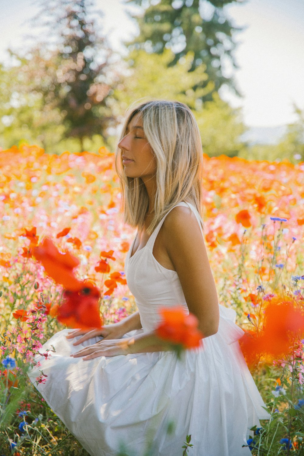 a woman in a white dress sitting in a field of flowers