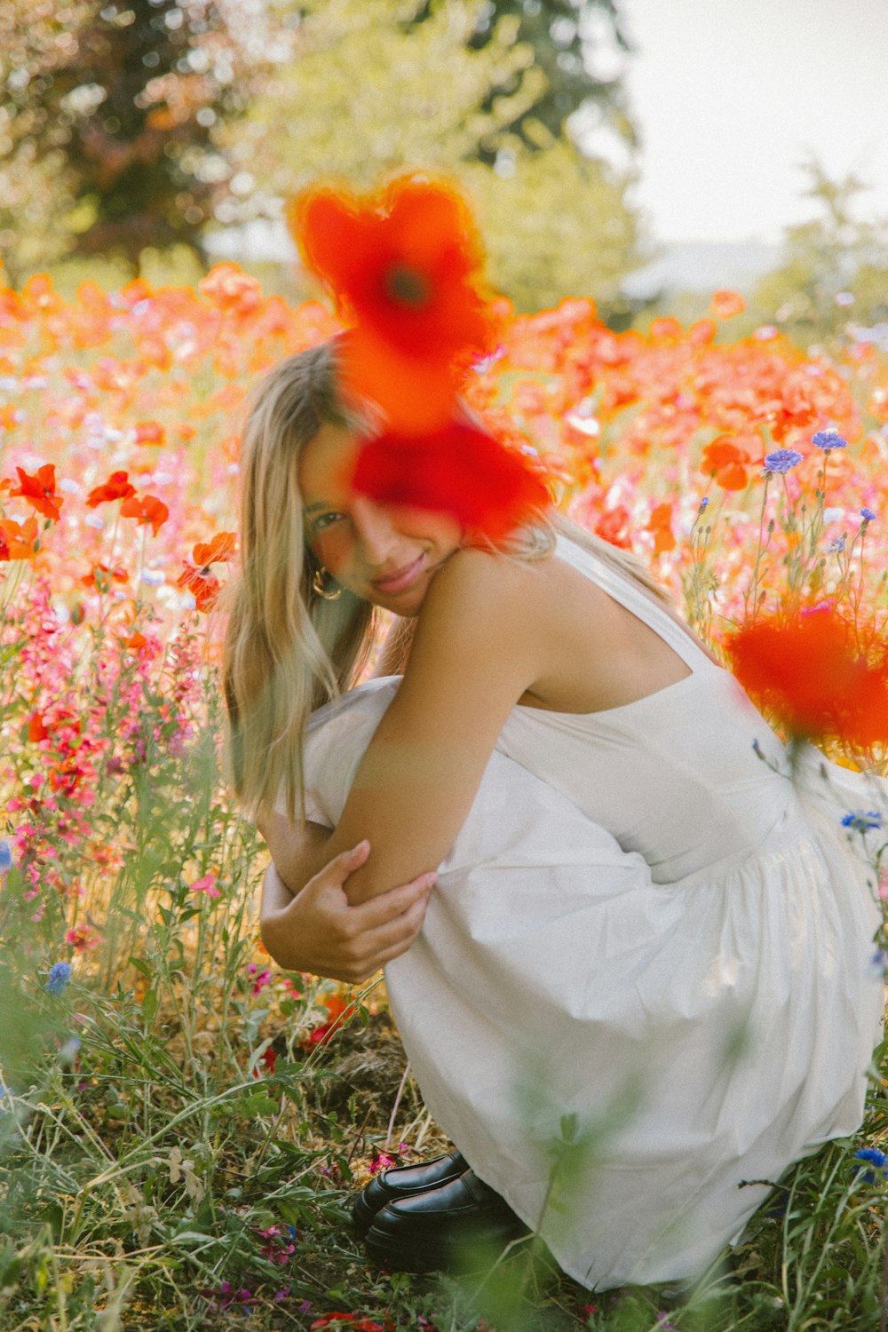 a woman kneeling down in a field of flowers