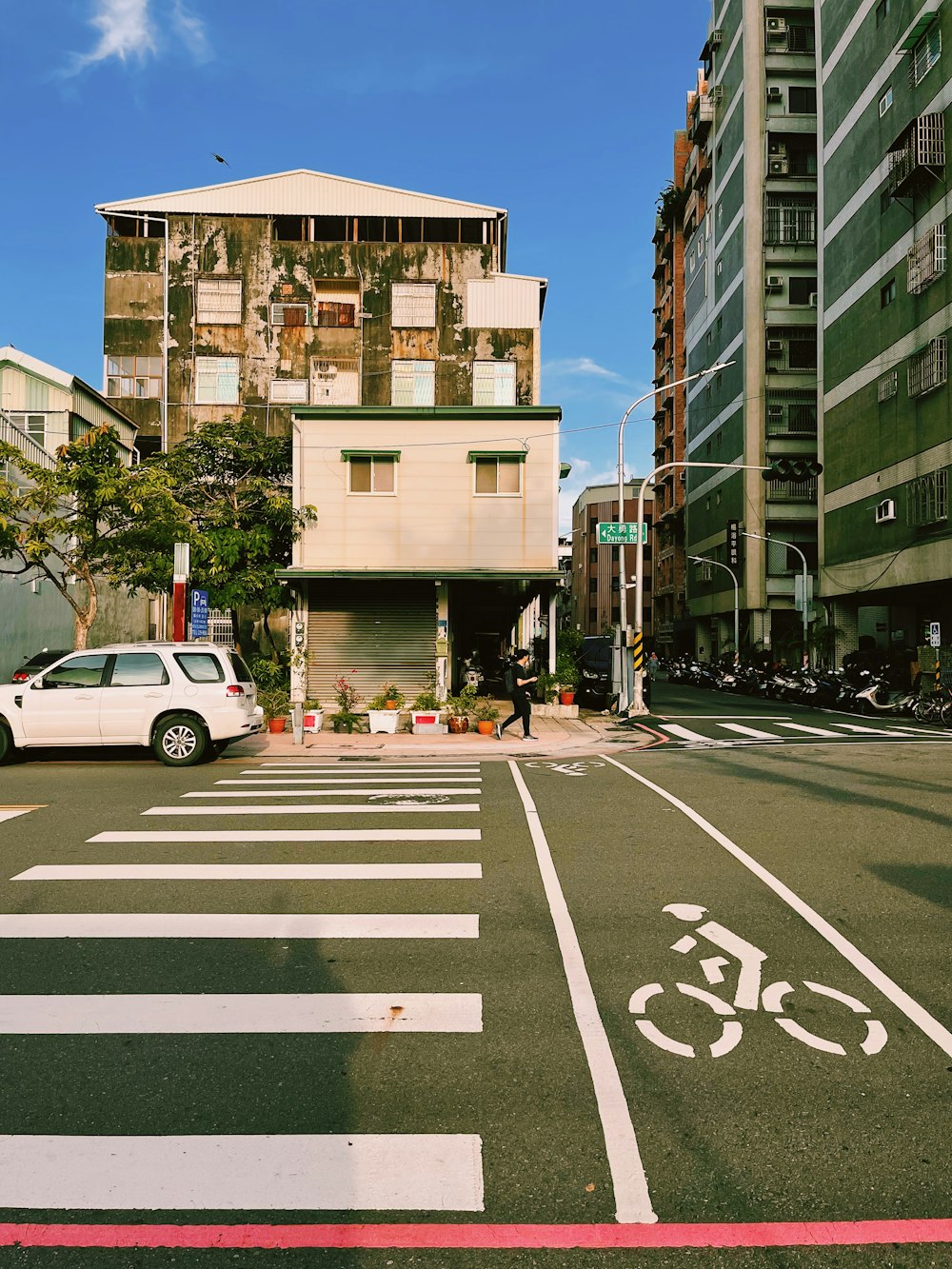 a white car driving down a street next to tall buildings