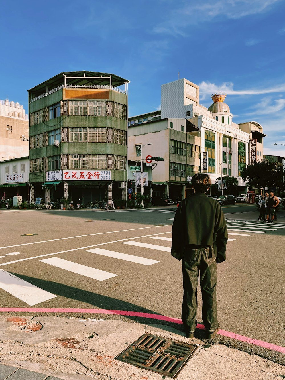 a man standing on the side of a road next to a building