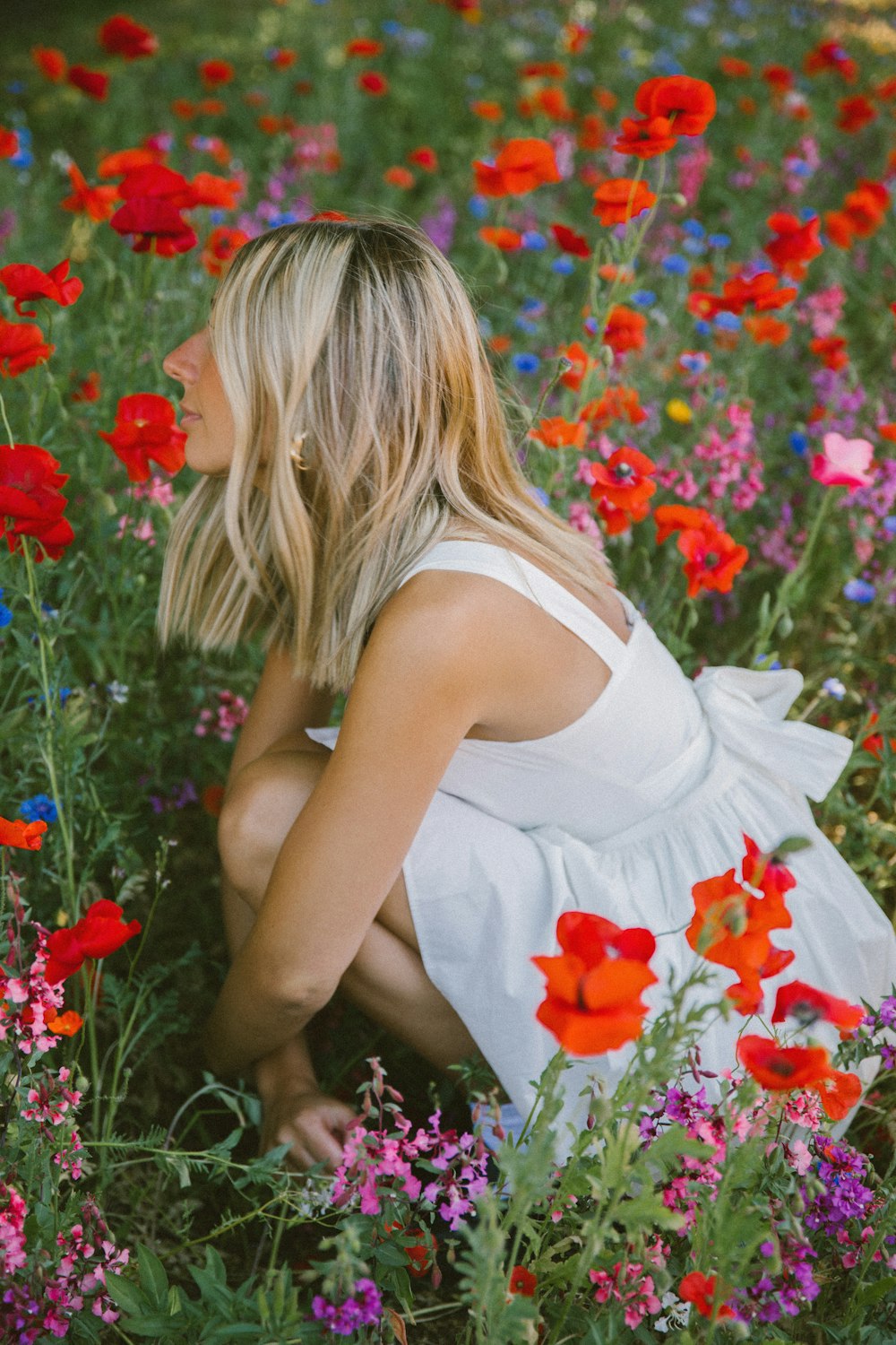 a woman kneeling down in a field of flowers
