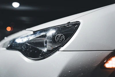 Before-and-after comparison of a foggy headlight restored to pristine clarity on a luxury sedan.