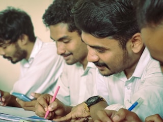 a group of men sitting at a table writing on paper