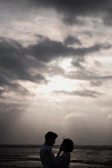A sweeping outdoor scene at dusk with the couple silhouetted against a dramatic sky.